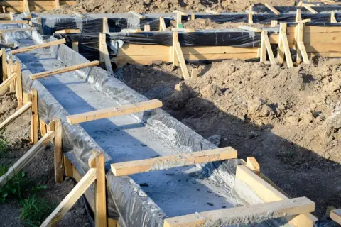 Wykonanie fundamentów: szalunek z folią i świeżym betonem.